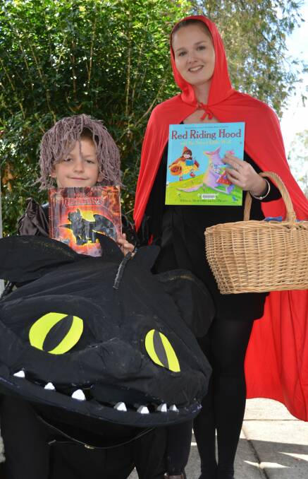 Zarlie the dragon holds his favourite book 'How to Tame a Dragon' with teacher Laura Simpson as little red riding hood.