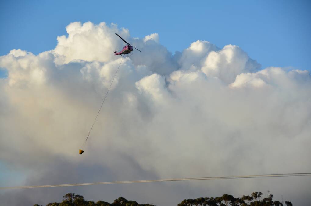 A helicopter drops water on the Clybucca fire currently burning near Kempsey.