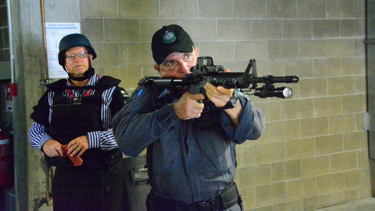 Straight shooter: Sergeant Michael Walker from the SPSU (State Protection Support Unit) demonstrates police weapons skills at the CAPP day at Kempsey Police Station. Macleay Vocational College principal Mark Morrison backs him up