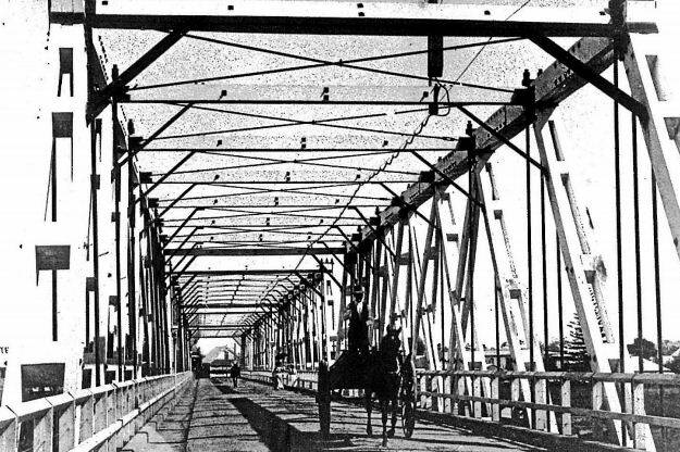 Kempsey traffic bridge looking from east to west in the 1910s.The Tattersall’s Hotel sign on the roof can be seen at the Kempsey end. Note the lamp, wooden spans and notice of speed limit to horse riders. Picture courtesy of the Macleay River Historical Society.
