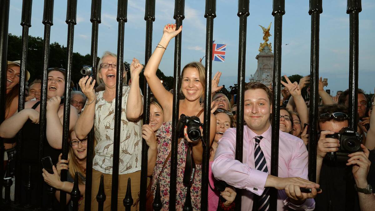 Crowds of people try to look at a notice formally announcing the birth of a son, placed in the forecourt of Buckingham Palace. Picture: Getty