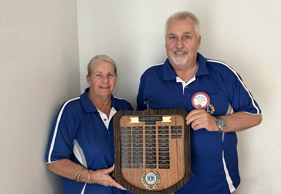 Crescent Head Lions Club member Jo Watts and club president Peter Loveday holding the Crescent Head Lions Club's Parade of Presidents board. Photo: Mardi Borg