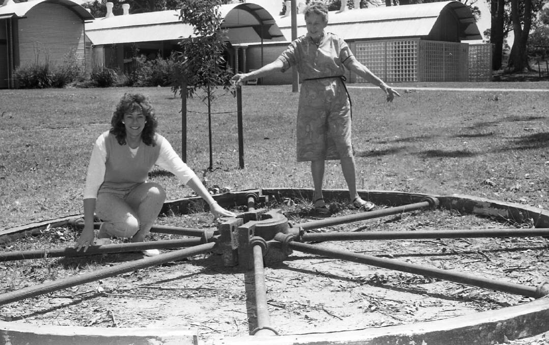 Betty McIntyre, volunteer at Kempsey Museum (standing) with Tourism Officer Michelle Angel, examining the flywheel from the Rollands Plains Mill in 1985. Photo from the Macleay Argus 