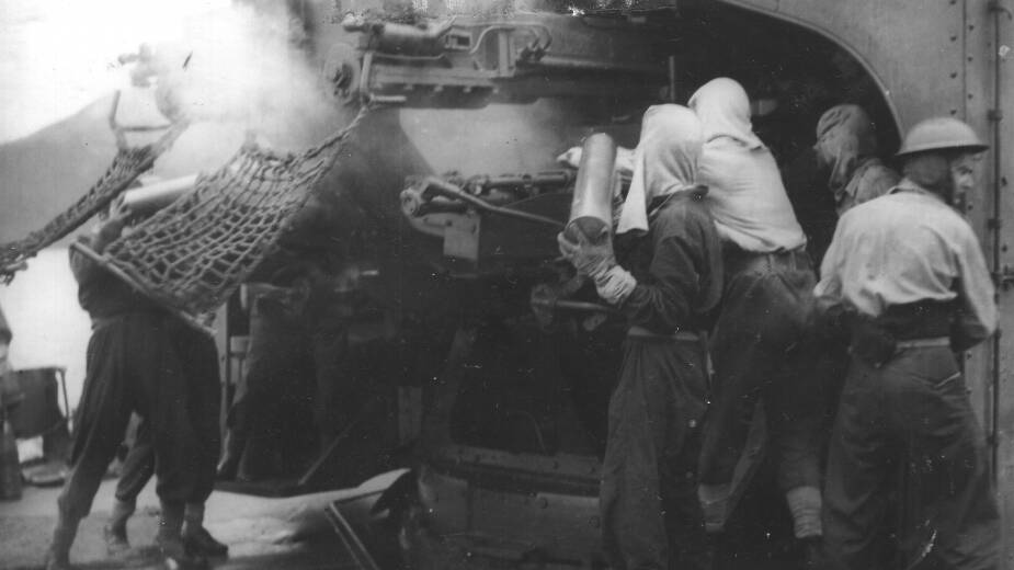 LOADING THE GUNS: Arunta crewmen load 4.7 inch ammunition during a bombardment. Photo: Royal Australian Navy.
