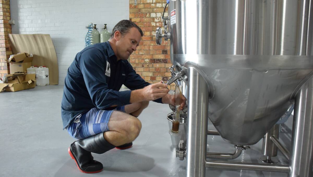 Homely brew: Sam takes a sample from one of the fermentation tanks. At the moment, Bucket Brewery produces three drinks - a German style black lager, a Munich style lager, and an American style pale ale. Photo: Lachlan Leeming. 