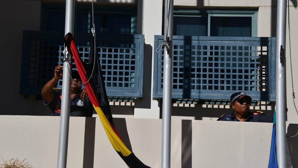 Raising the Aboriginal and Torres Strait Islander flags at a Mount Isa Naidoc Week event.
