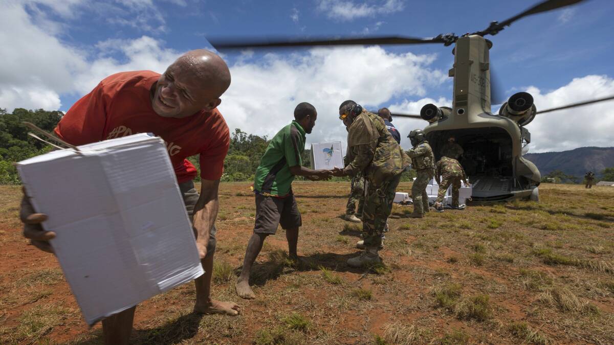 Papua New Guinea Defence Force personnel help local people move aid delivered by an Australian Army CH-47F Chinook helicopter during Operation PNG Assist 2018. Photo courtesy of the ADF.