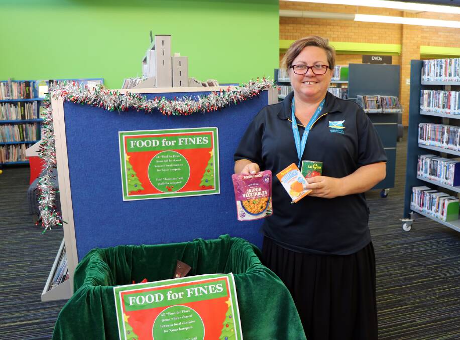 FINES CANNED: Kempsey Library's Natasha Harris at the Food for Fines donation box at Kempsey Library.