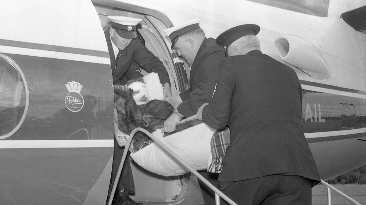 A bandaged Johnny OKeefe being put on a Fokker Friendship Airlines of NSW flight for Sydney by Ambulance Officers R Myhill and Charles Martin. Photo: Macleay Argus.