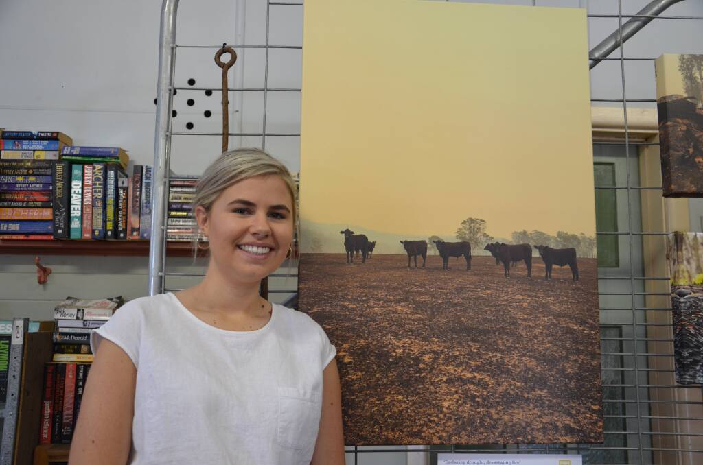 Sally Argue with one of her photos in the exhibition 'Enduring drought, devastating fire'