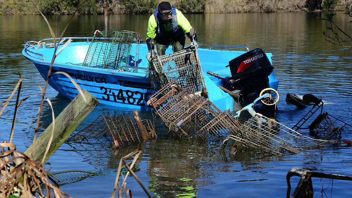 What a mess: a contractor hired by the RMS battles with trolleys in the Macleay River last Friday.