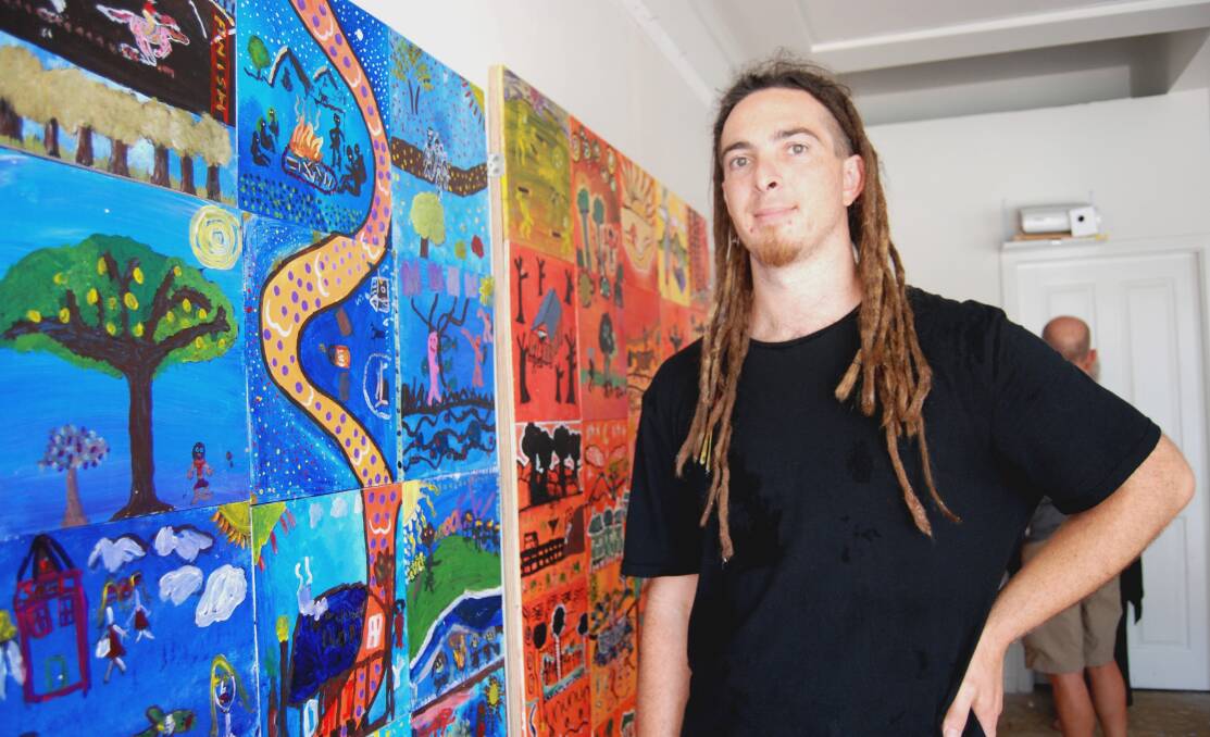 Facilitator Sam Taylor with a colourful mural created by local students. The mural, along with a variety of other works, are currently on display at the Artmakas pop-up gallery on Belgrave Street, Kempsey.  
