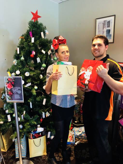 Festive spirit: Kempsey Macleay RSL Club employees Sonya Reid and Rodney Daley next to the tree for your reference. Photo: Supplied.
