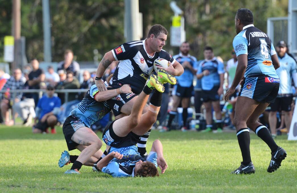 Tough carry: Magpies Coach Bo Wilson carries the ball forward and knocks a Marlins player to the ground earlier this season. Photo: Penny Tamblyn.