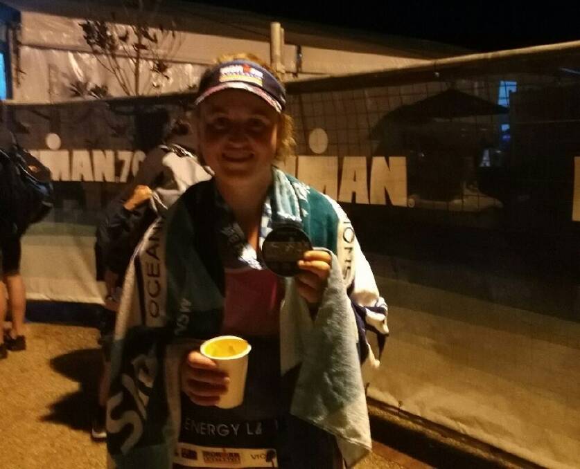 Exhausted: Megan Clarke proudly holds up her medal after completing the Ironman Australia. Photo: Supplied.